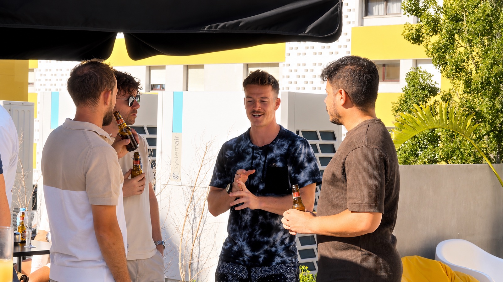Attendees in conversation with drinks under a shade canopy on a rooftop terrace in Lisbon